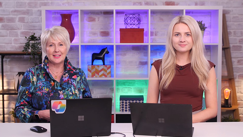 Two women working on laptops at a table.