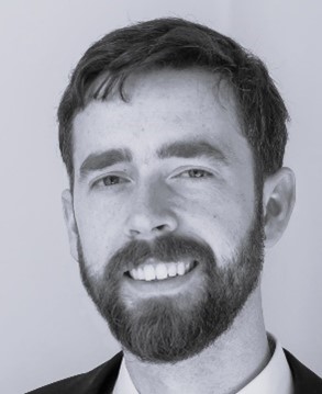 a man wearing a suit and tie smiling and looking at the camera