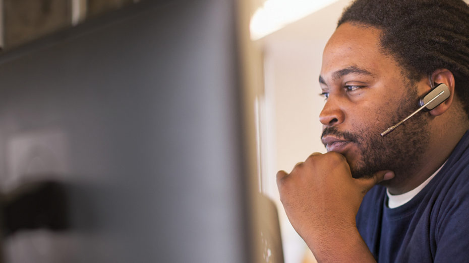 Image of a firstline worker looking at several computer monitors.