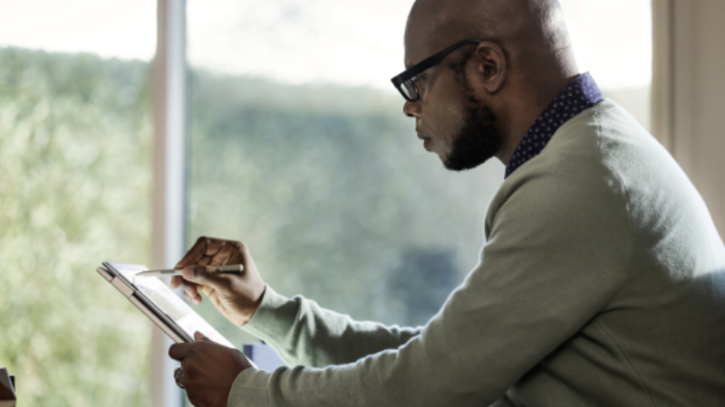 Man working on a tablet, possibly sketching, designing, or taking notes.