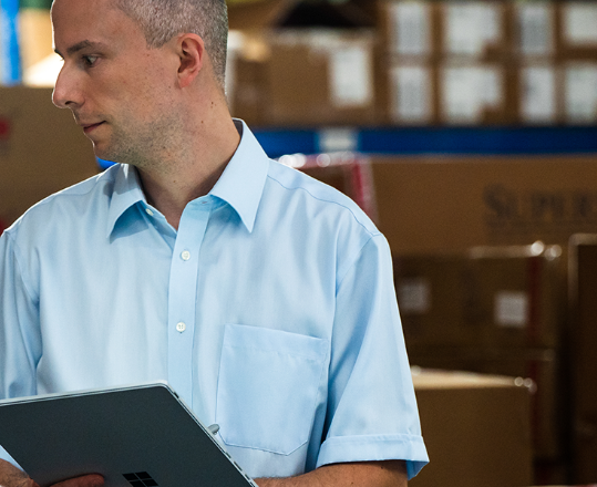 A man in a warehouse working with a tablet in his hand