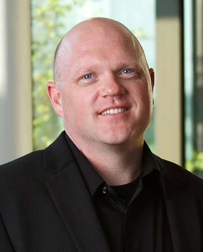 a man wearing a suit and tie smiling and looking at the camera