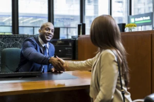 Two business people shaking hands across a table.