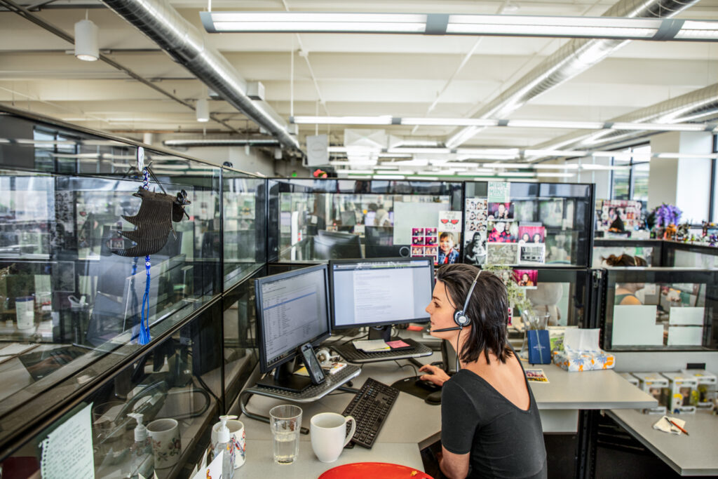 Photo of a female call center employee working at a cubicle desk.