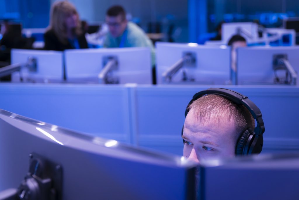 Person wearing headphones and working on dual monitors