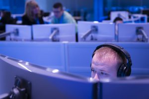Person wearing headphones and working on dual monitors