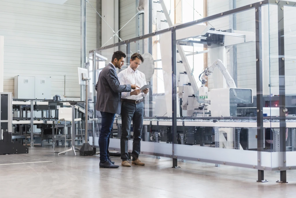 Two businessmen with tablet talking in modern factory