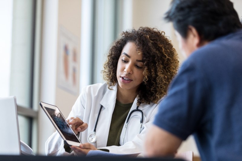 A physician showing something on a tablet to a person.