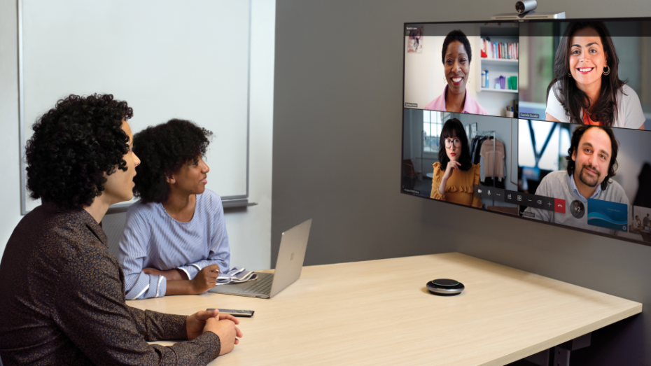 Two coworkers in conference room on a Microsoft Teams call with four other people
