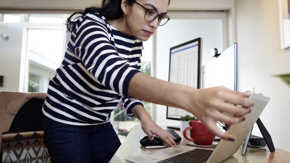 Female working remotely from her home office on an HP Elitebook device, standing at her desk.