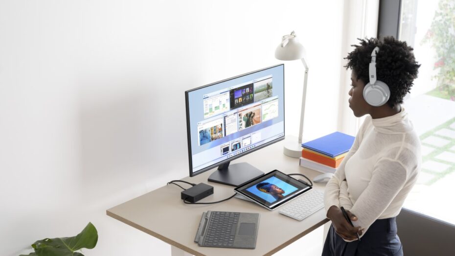 Contextual photography of adult female using Surface Pro 8 docked with Surface Headphones.