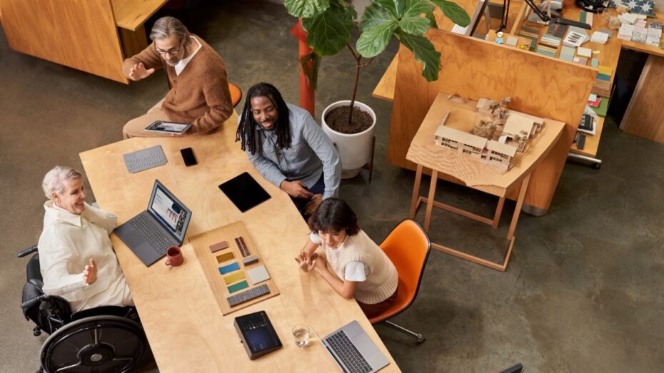 People in the conference room joining on a laptop via Companion Mode while a remote participant presents during a Microsoft Teams Room (M T R) meeting​.