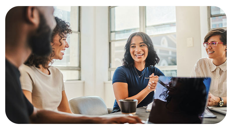 A diverse group of coworkers collaborate in an office space while one takes notes on his laptop