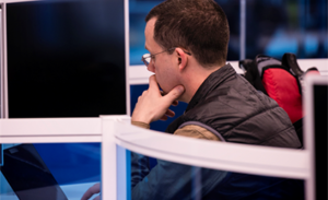 A tech worker stares at a computer monitor..