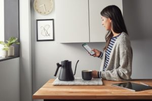 Woman working in Excel on Android phone inside in the kitchen.