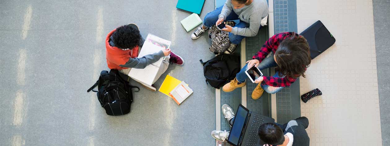 O vedere aeriană a unui grup de studenți care studiază cu laptopuri, tablete și smartphone-uri