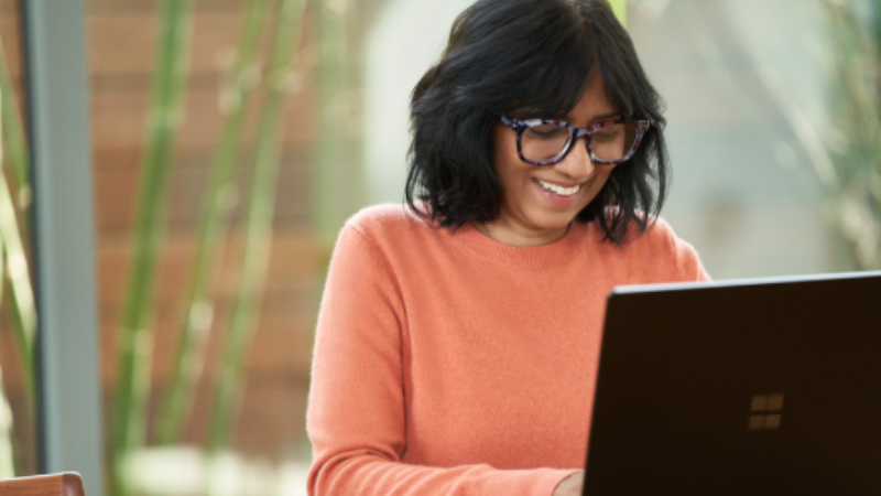 Mujer sonriendo mientras trabaja en su computadora portátil.