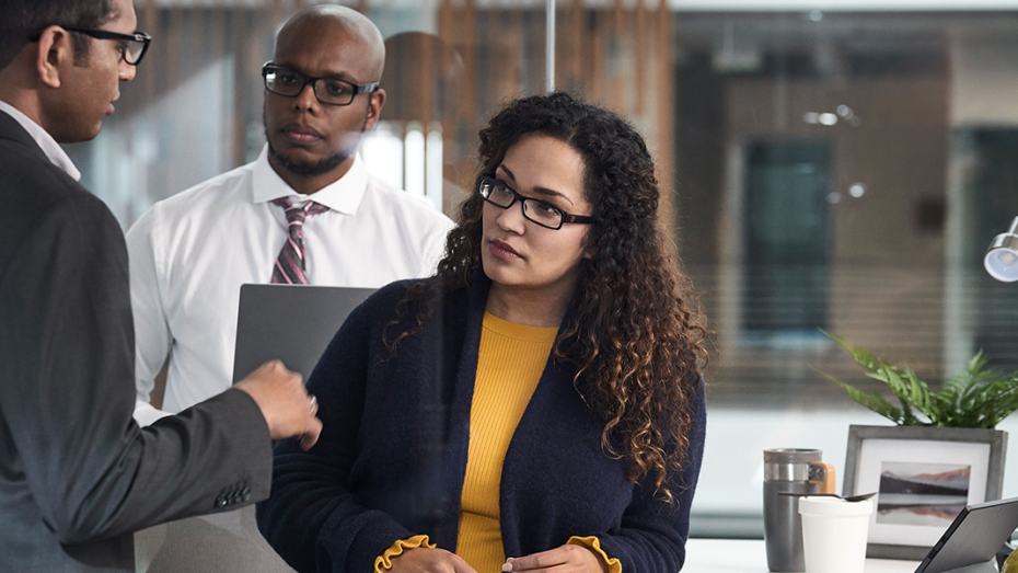 Image of three workers collaborating beside a desktop.