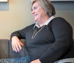 Erinn Rominger sits on the couch and looks to her left.