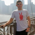 Sydorchuk stands in front of a bridge and smiles at the camera.
