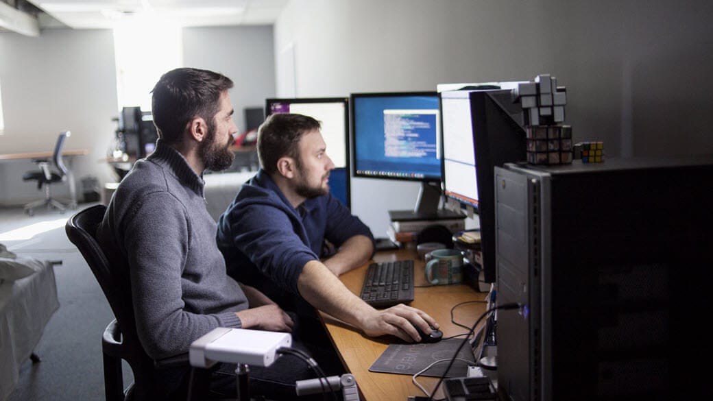 Two co-workers look at a monitor.