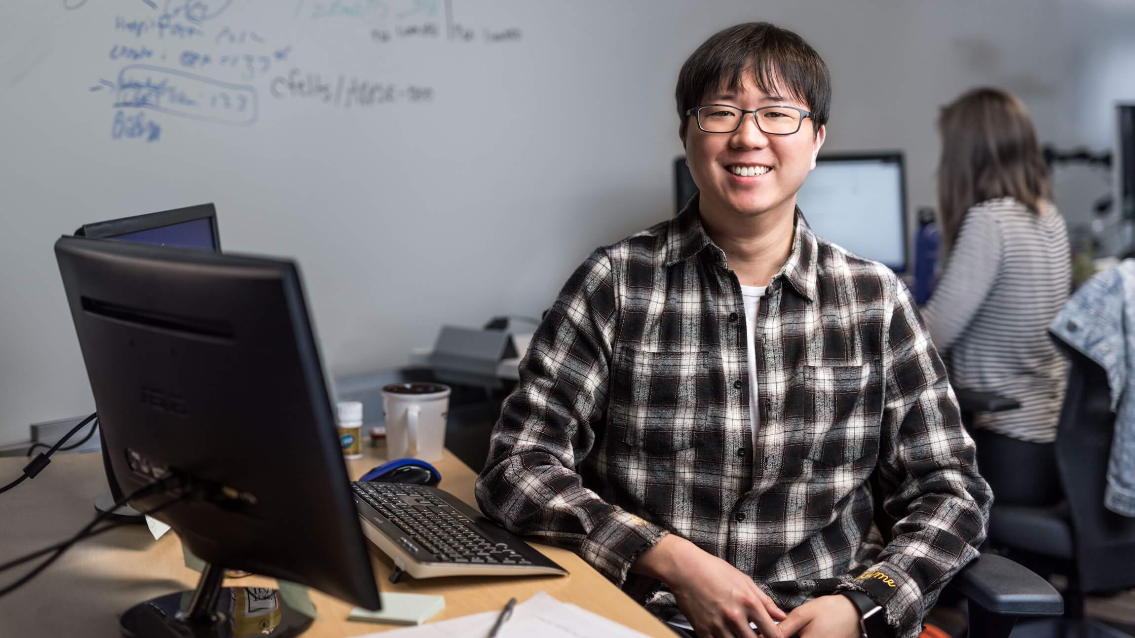 Portrait of male developer in glasses and plaid flannel shirt, smiling and facing camera.