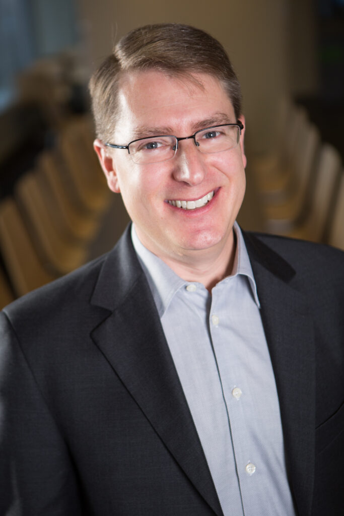 Osten poses in a professional headshot.