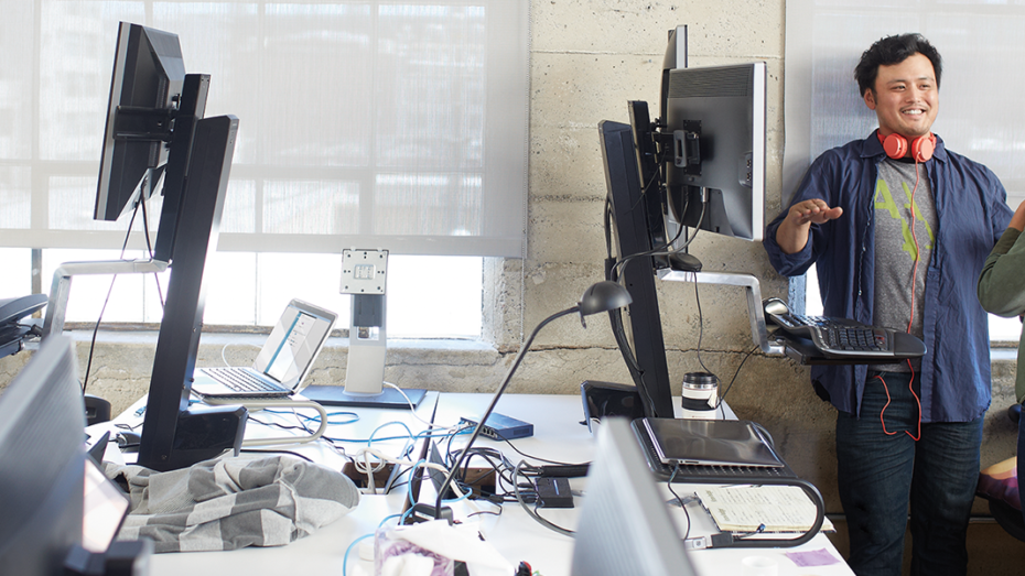 Image of two coworkers meeting next to a computer in their office.