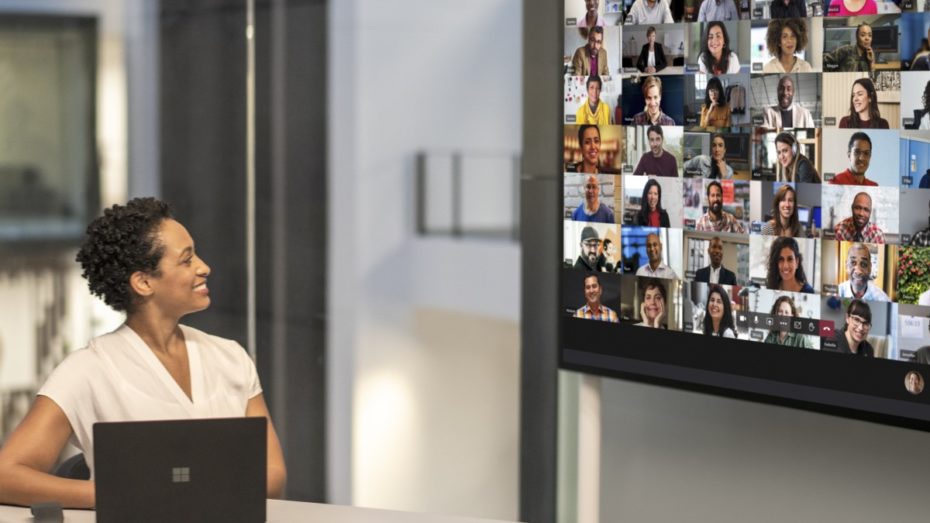 Adult female meeting in a conference room while using Microsoft Teams Together Mode on a Surface Hub 2S 85” device.
